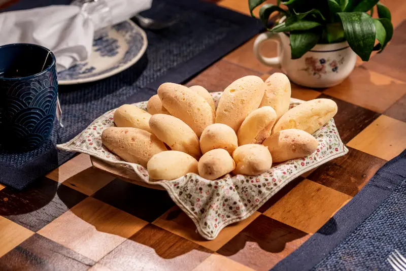 Uma cesta com pães de queijo provolone em cima de uma mesa